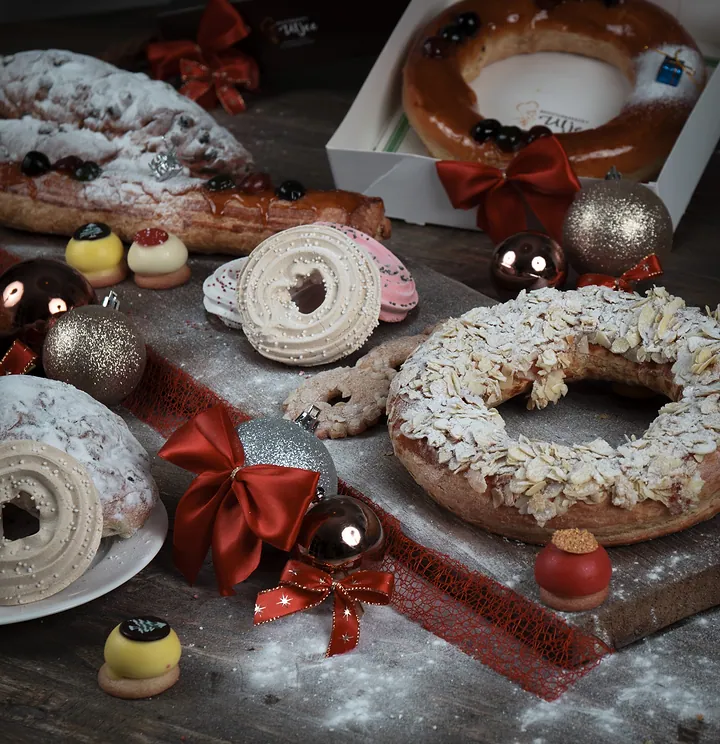 Kerststol, amandelkransen en kerstgebak op een donkere tafel